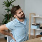 Man in pain at desk holding back